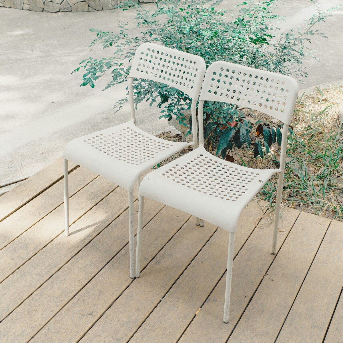 Two white chairs on a wooden deck